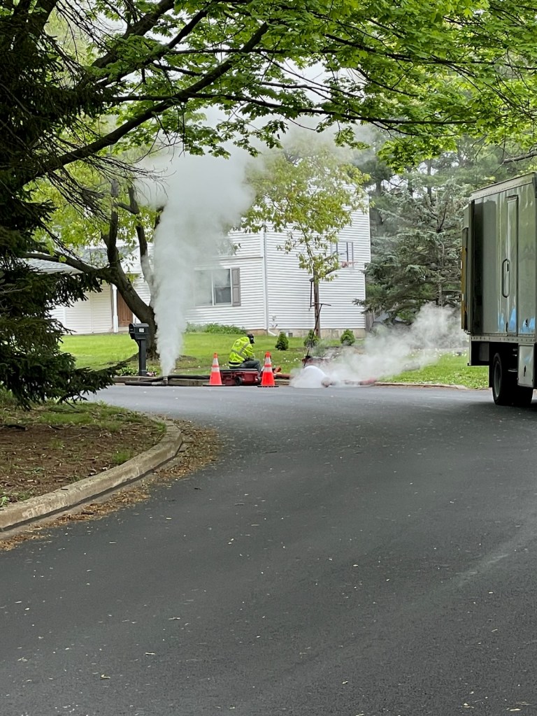 A picture of a neighborhood with smoke coming out of the sewage system