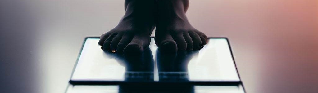 A picture of just the feet of someone standing on a scale.